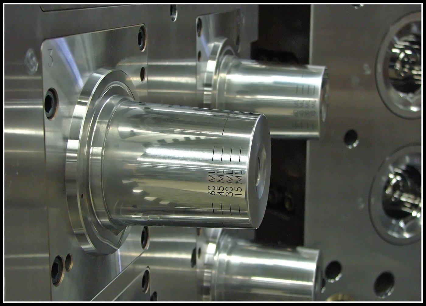 Close-up of a precision-machined injection mold cavity insert for a graduated medical dosing cup