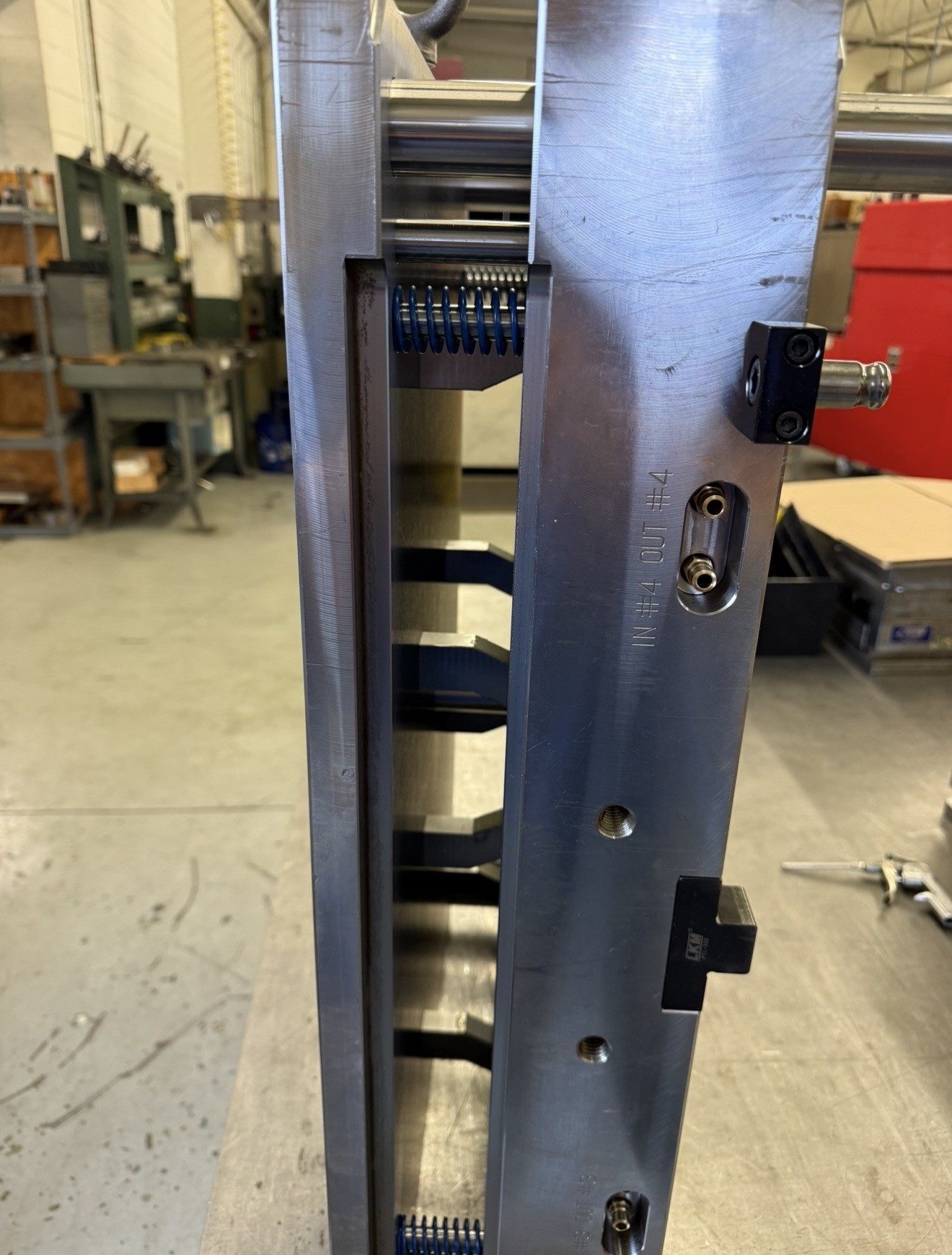 A machined mold component with labeled cooling line ports, marked IN number 4 and OUT number 4