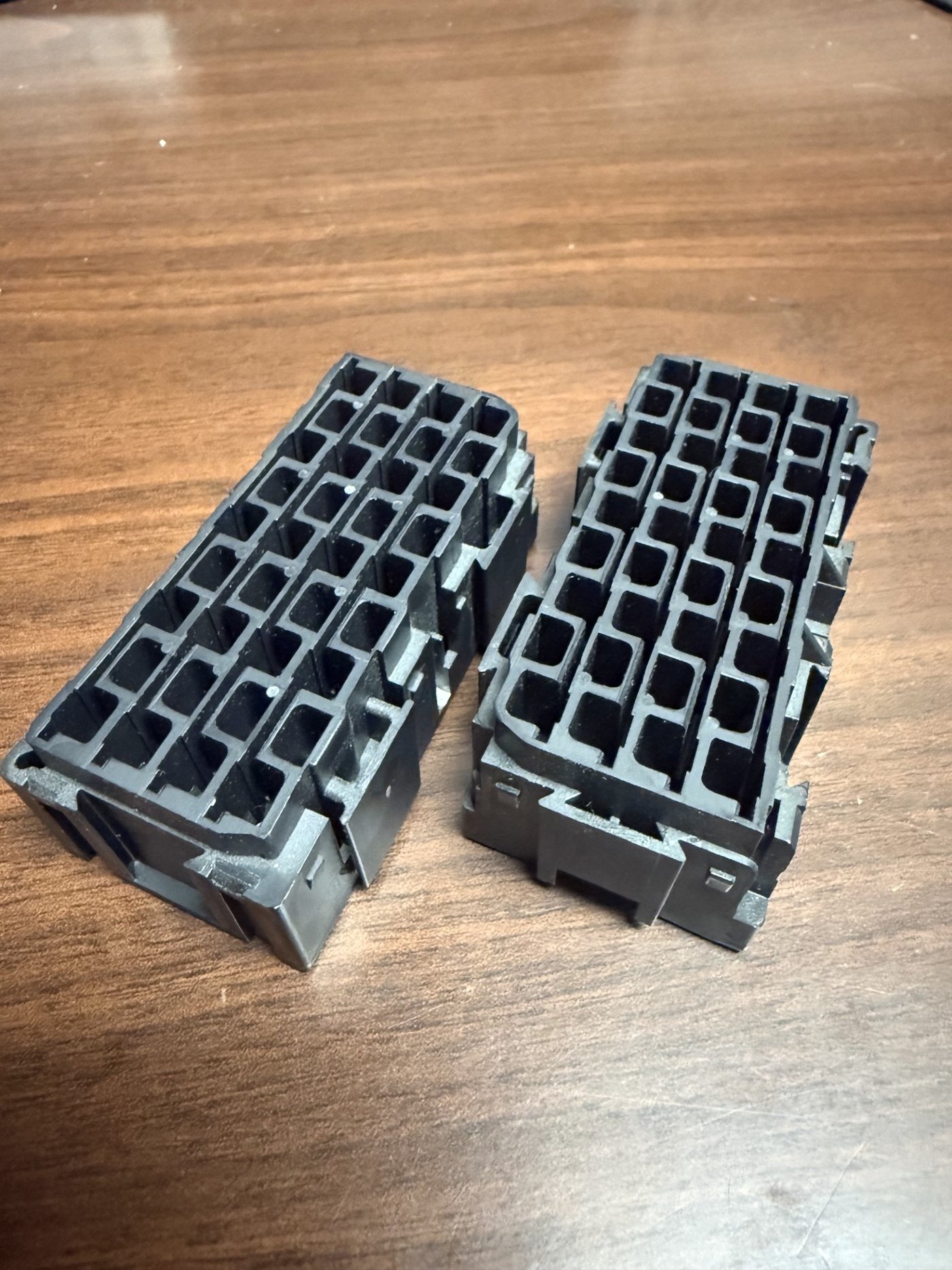 Two finished injection-molded connector housings, black plastic