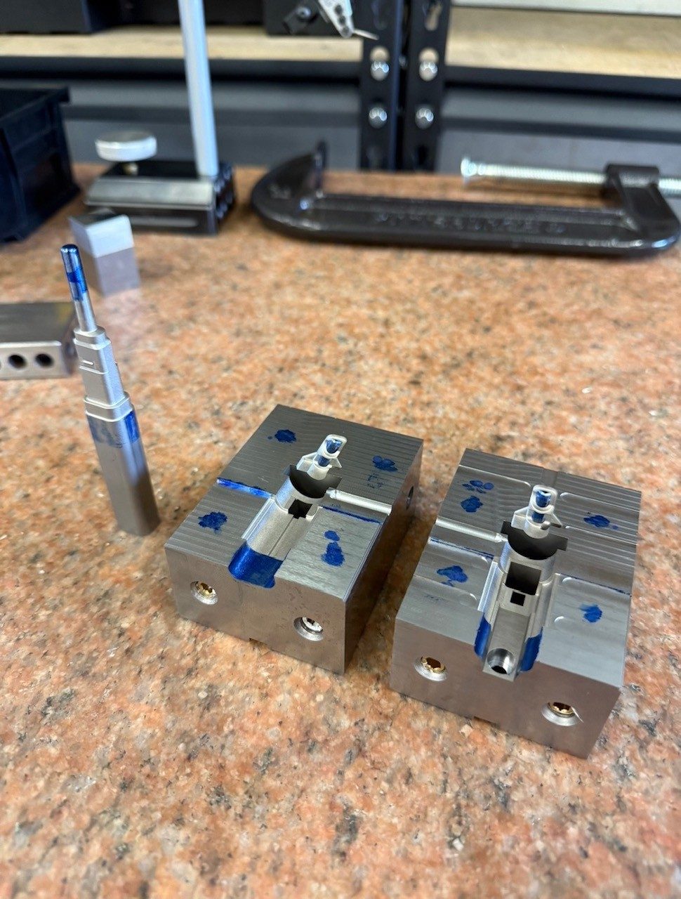 Two small mold blocks marked with blue layout dye, on a workbench