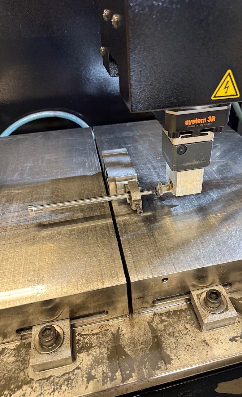 A small workpiece held in a precision machine setup, clamped for measurement or machining