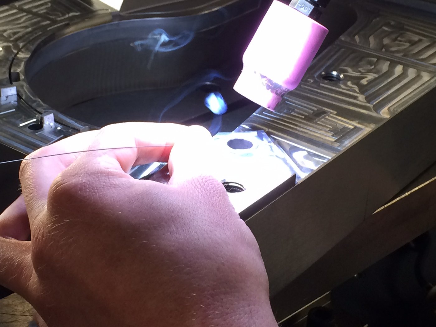 A mold maker's hands doing detail texturing work on a mold cavity plate